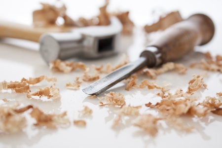 hammer and chisel on a white board with sawdust shavingsの写真素材