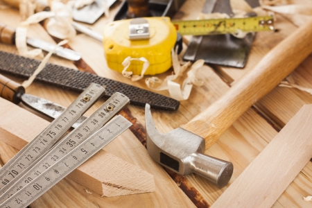 carpenter tools,hammer,meter,chisel and shavings over wood tableの写真素材