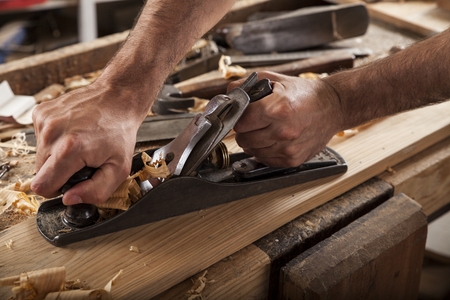 carpenter working with plane on wooden backgroundの写真素材