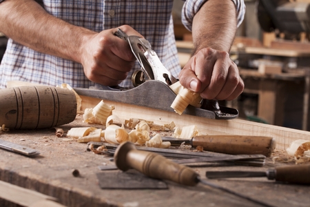 carpenter working with plane on wooden backgroundの写真素材