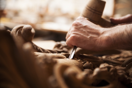 Hands of craftsman carve  with a gouge in the hands on the workbench in carpentryの写真素材