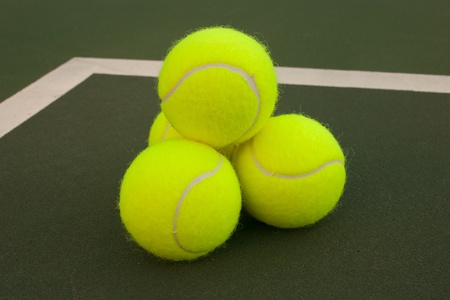 New yellow tennis balls on a green courtの写真素材