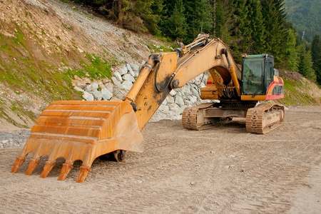 A yellow digger or excavator used to prepare a new track in the mountains