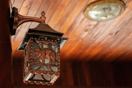 Lantern hanging on a wooden ceiling with a clock in the backgroundの写真素材