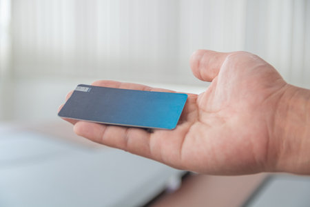 Close up of male hand holding blue credit card, shallow depth of field