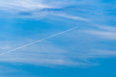 Airplane in the blue sky with white clouds, airplane trail.の写真素材