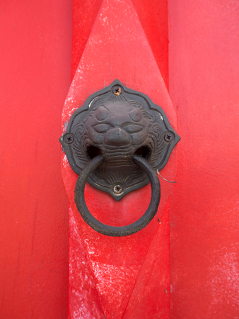 Old red door in the temple gate with ring knocker.の写真素材