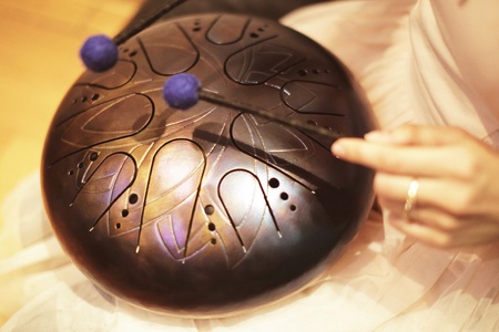 woman is playing on the steel tongue drum on the floorの写真素材