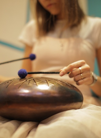 woman is playing on the steel tongue drum on the floor