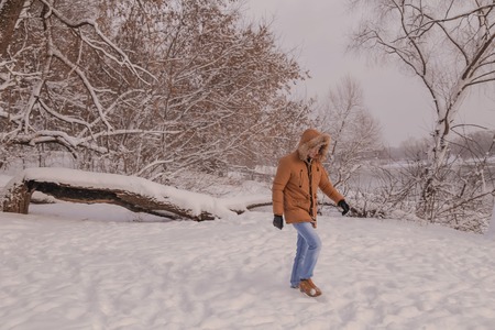 young man in a brown jacket is walking in a forestの写真素材