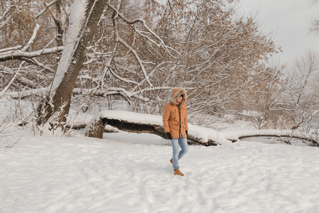 young man in a brown jacket is walking in a forestの写真素材