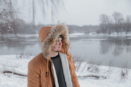 young man in a brown jacket is walking in a forestの写真素材