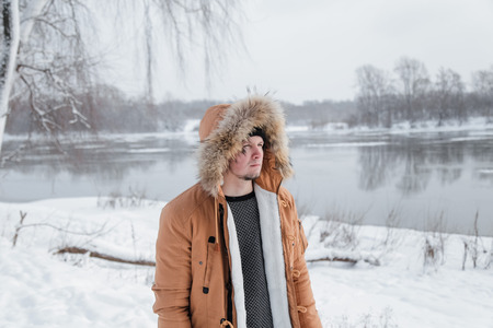 young man in a brown jacket is walking in a forestの写真素材