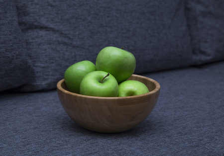 Green fresh apples are in a wooden bowl in the kitchenの写真素材
