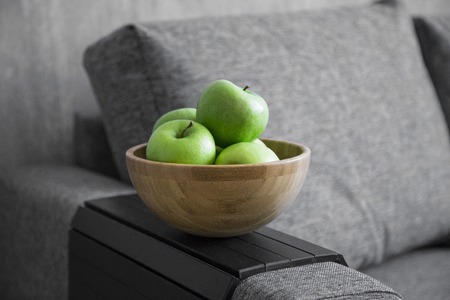 green fresh apples are in a wooden bowl in the kitchen