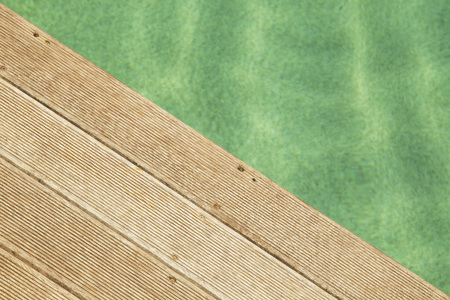 blue water in the pool on the background of a wooden floor with green tree