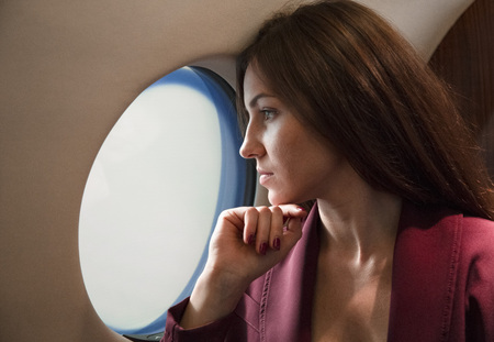 beautiful young woman sits in a plane near the windowの写真素材