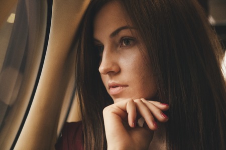 beautiful young woman sits in a plane near the windowの写真素材