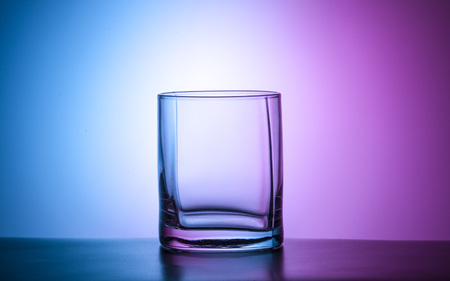 Glass of water with color  on the mirror table isolatedの写真素材