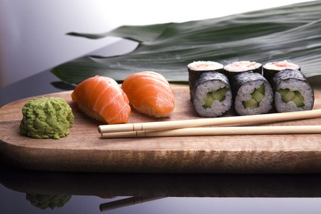 Set of sushi on a wooden board with leaves of plants on a darkの写真素材