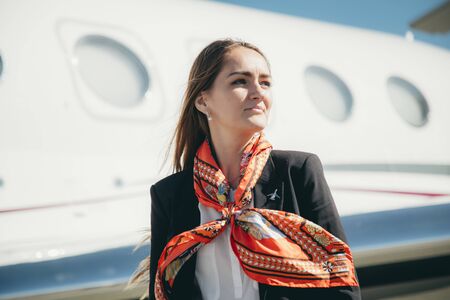 Beautiful young business woman near the airplane jet at sunny day in airportの写真素材