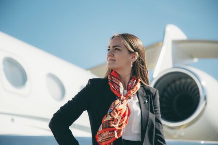 Beautiful young business woman near the airplane jet at sunny day in airportの写真素材