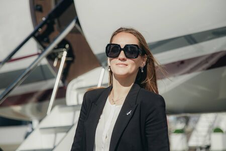 Beautiful young business woman near the airplane jet at sunny day in airport