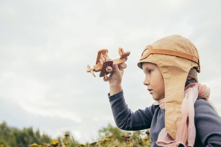 Cute little boy in a pilots suit is playing with a toy plane near the airportの写真素材