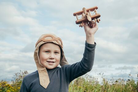 Cute little boy in a pilots suit is playing with a toy plane near the airportの写真素材