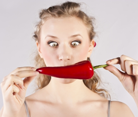 Beautiful woman teeth eating red hot chili pepperの写真素材