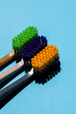 three toothbrushes (green, purple, orange) close upの写真素材