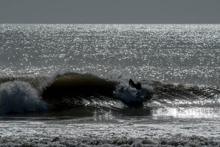 Silhouette of a surfer riding the waves at dusk in Floridaの写真素材