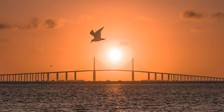 The sun rises behind a bridge in central Floridaの写真素材