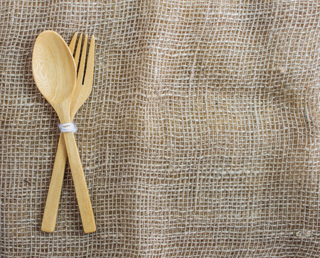 Closeup wooden of spoon and fork set on sackcloth background. Top view with empty for copy space.