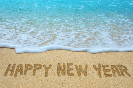 Happy new year written on sandy beach.の写真素材