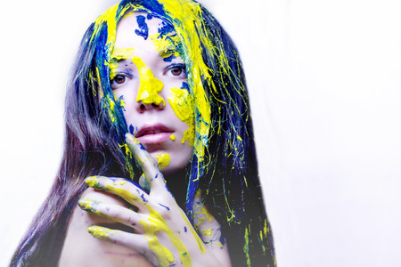 Beauty portrait of woman painted blue and yellow on white background