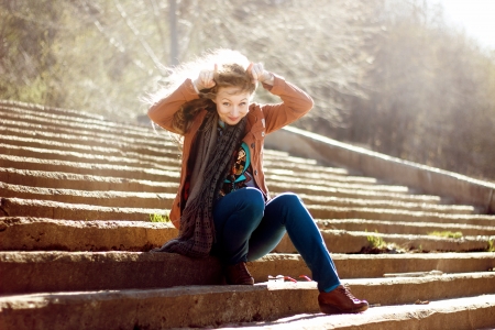 Funny woman with blonde curly hair on stairs backgroundの写真素材