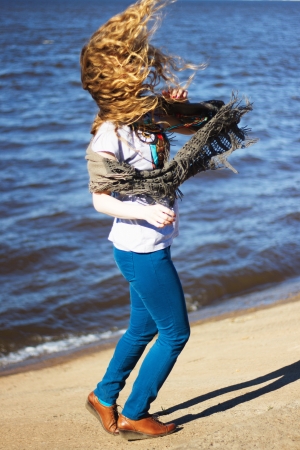 Woman with flying blonde curly hair on sea backgroundの写真素材