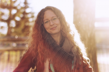 Happy woman with glasses and curly hair on sunny backgroundの写真素材