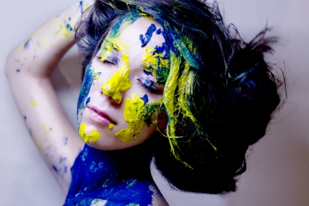 Beauty fashion portrait of woman painted blue and yellow on black backgroundの写真素材