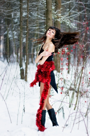 Beautiful woman with bright tinsel in winter forestの写真素材