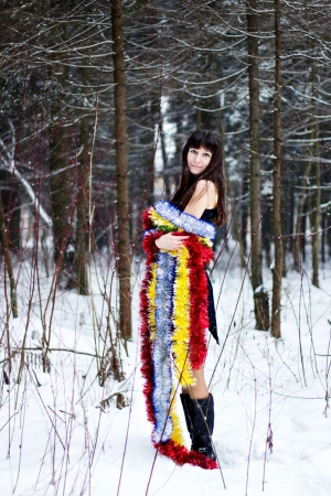 Beautiful woman with bright tinsel in winter forestの写真素材