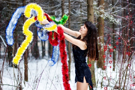 Beautiful woman with bright tinsel in winter forestの写真素材