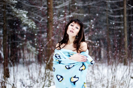 Beautiful woman under warm cute wrap in cold snow forestの写真素材