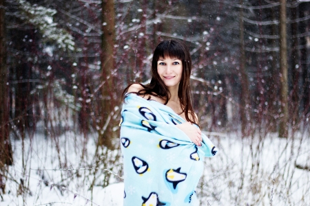 Beautiful woman under warm cute wrap in cold snow forestの写真素材