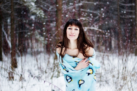 Beautiful woman under warm cute wrap in cold snow forestの写真素材