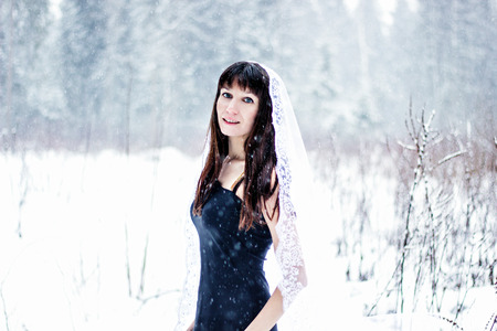 Beautiful smiling bride under veil on white snow backgroundの写真素材