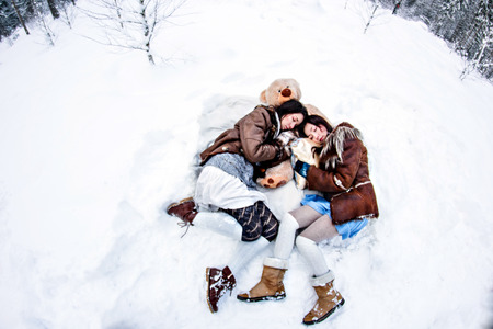 Fashion women lying on white snow winter background fisheyeの写真素材