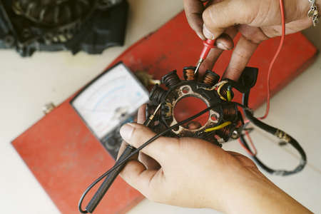 technician holding and check magnetic motor coil,generator coil of scooter or motorcycle with...