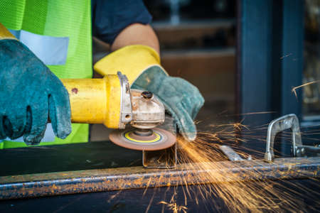 worker hand working by Electric grinder industry tool cutting steel with split fire use for...